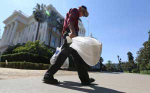 man_carries_plastic_single_use_bags_past_the_Capitol_in_Sacramento